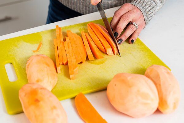 slicing sweet potatoes on a cutting board