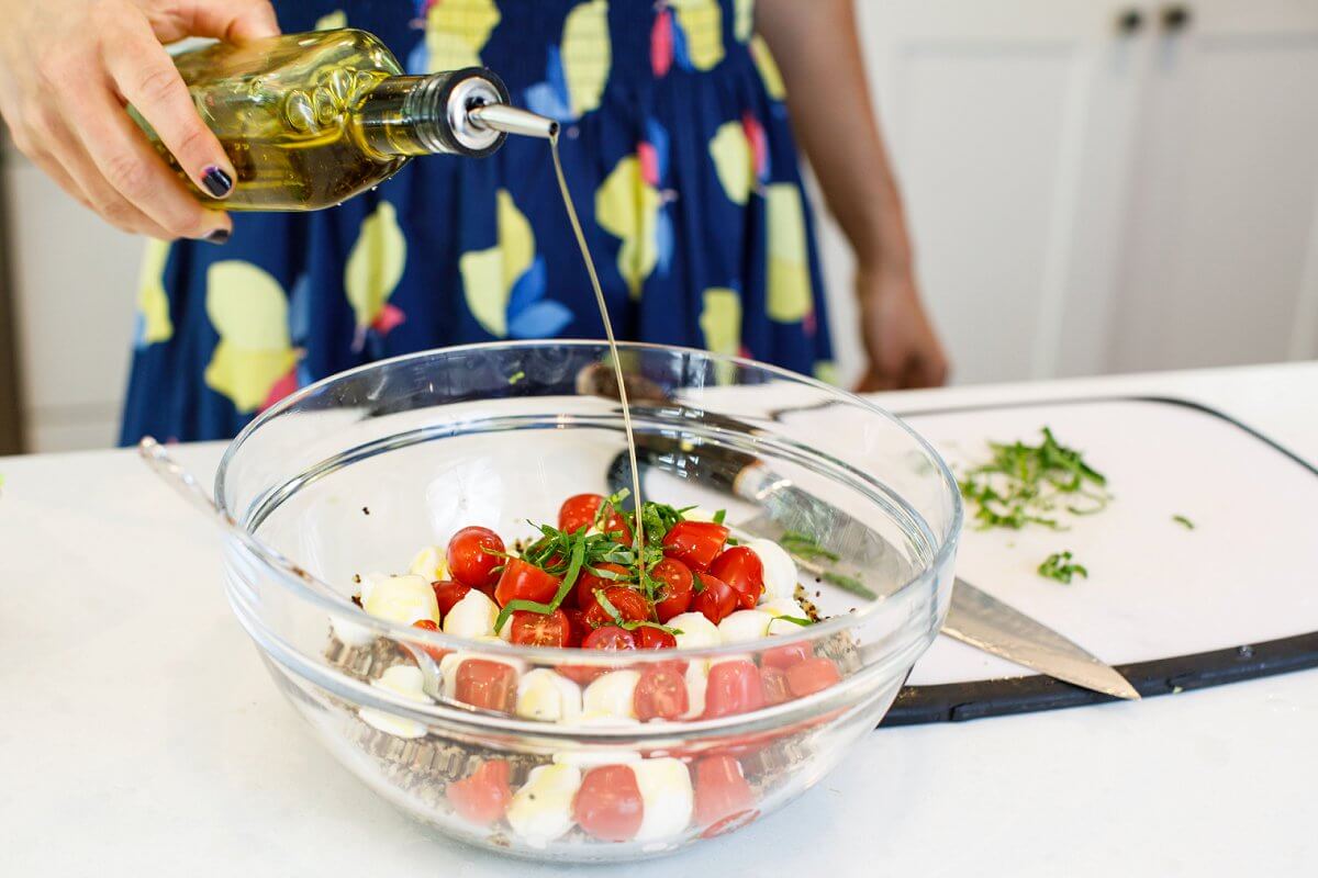 Liz pouring olive oil into Caprese Quinoa Salad