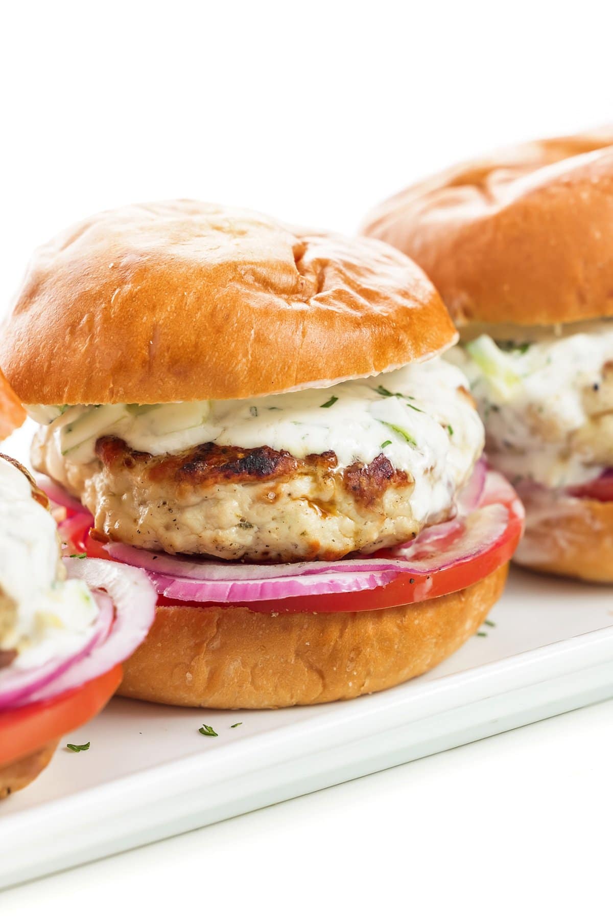 Greek Turkey Burgers with Tzatziki Sauce assembled on a tray.