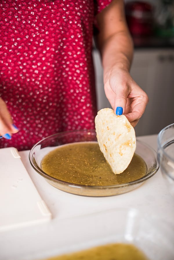 dipping corn tortillas in salsa verde