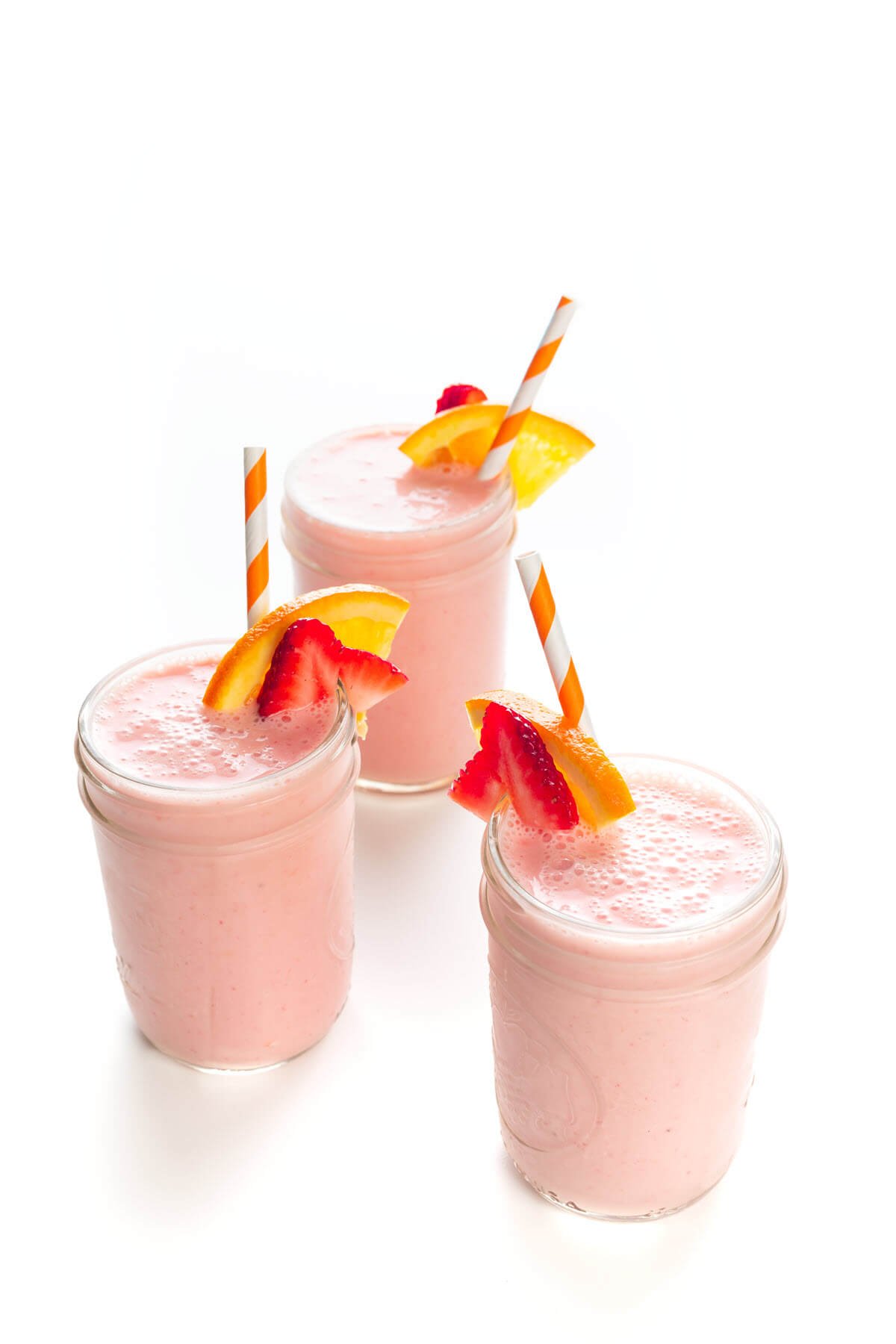 3 Strawberry Sunrise Breakfast Smoothies with straws in mason jars.