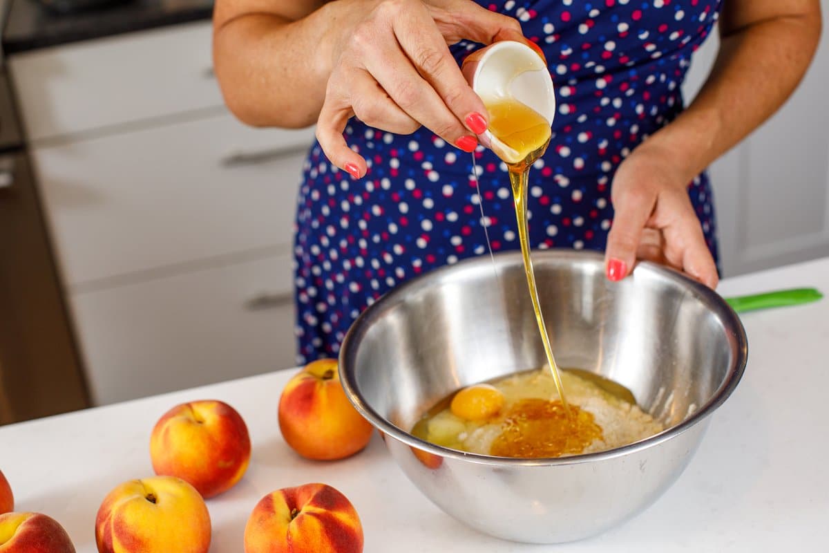 Pouring honey into metal bowl with almond flour and eggs.