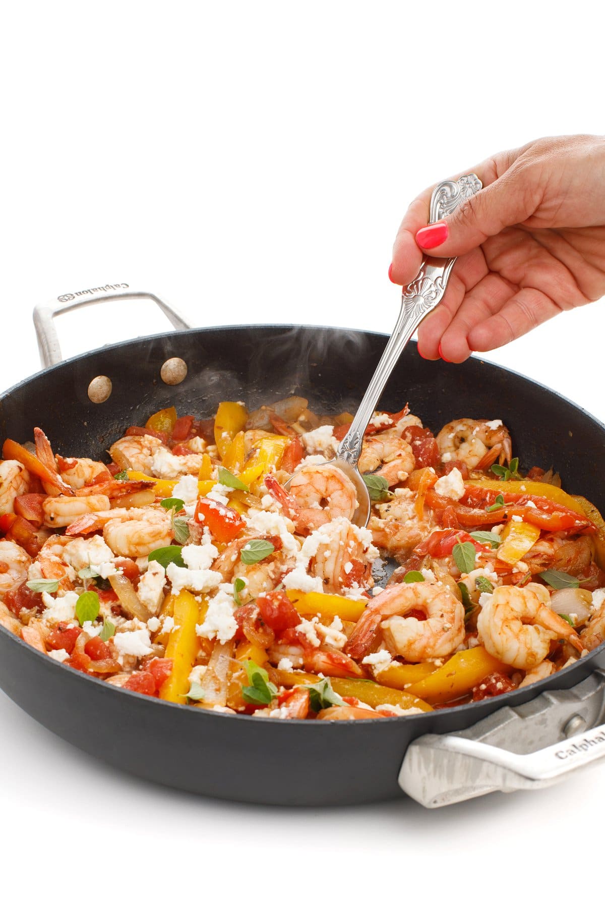 Scooping a fork into the pan of Mediterranean sautéed shrimp.