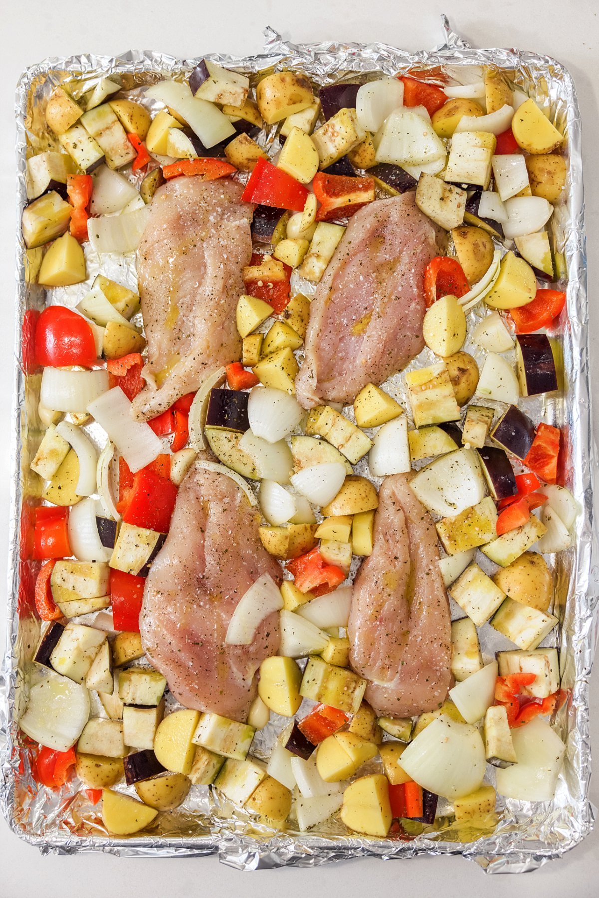 Sheet pan Greek chicken and vegetables ready for the oven.