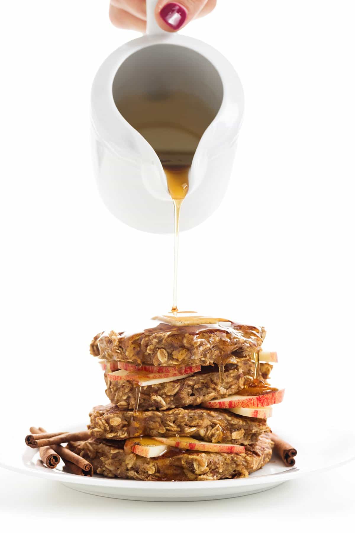 Pouring syrup on a stack of apple cinnamon protein pancakes