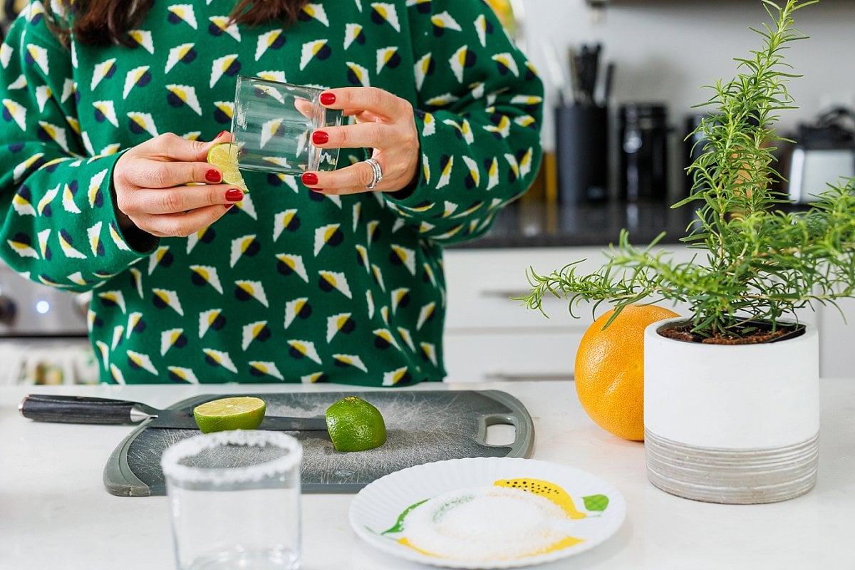 Liz running a lime wedge around the rim of a glass tumbler.
