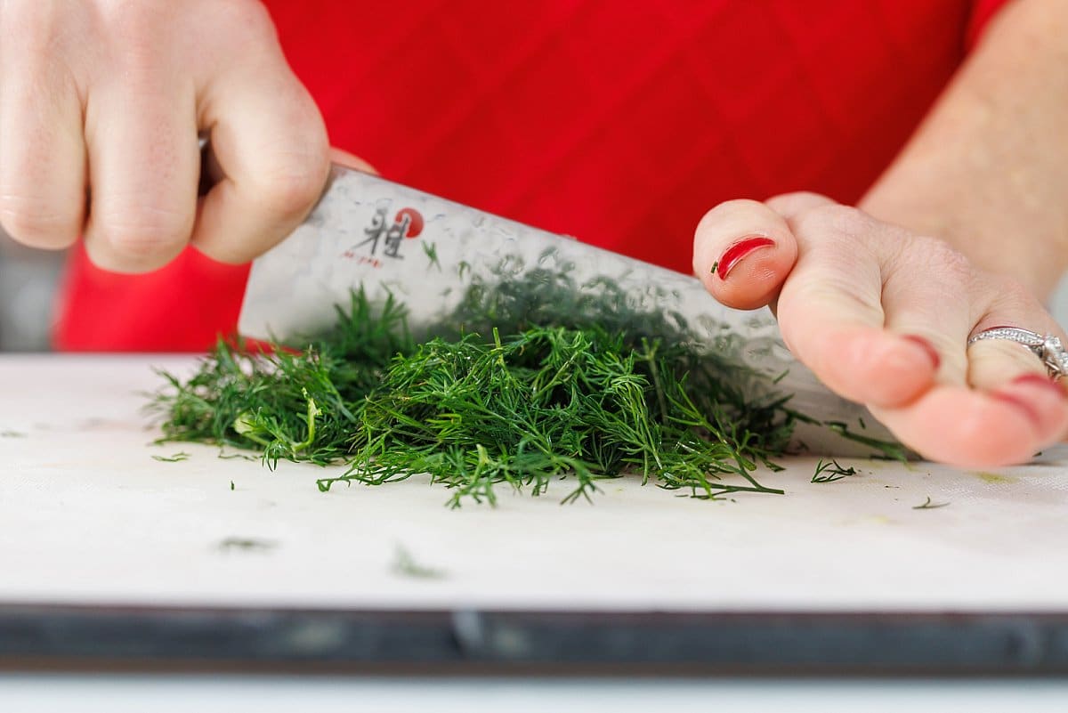 Liz mincing fresh dill with a sharp knife.