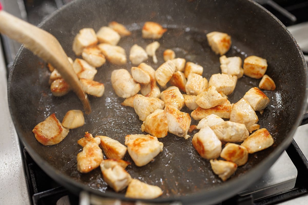 Cooking cubed chicken in a pan.