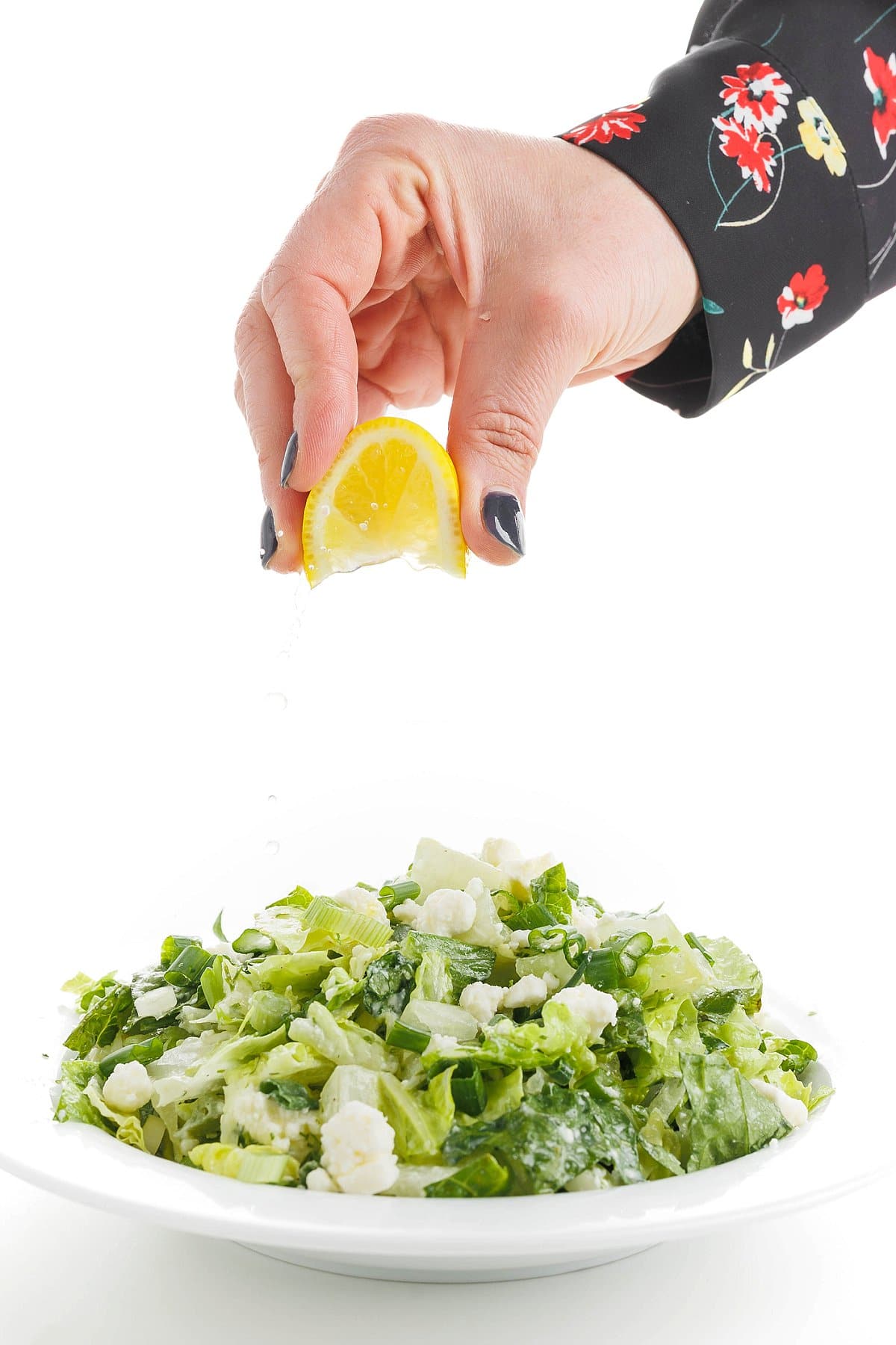 Garnishing Greek herb salad with feta.