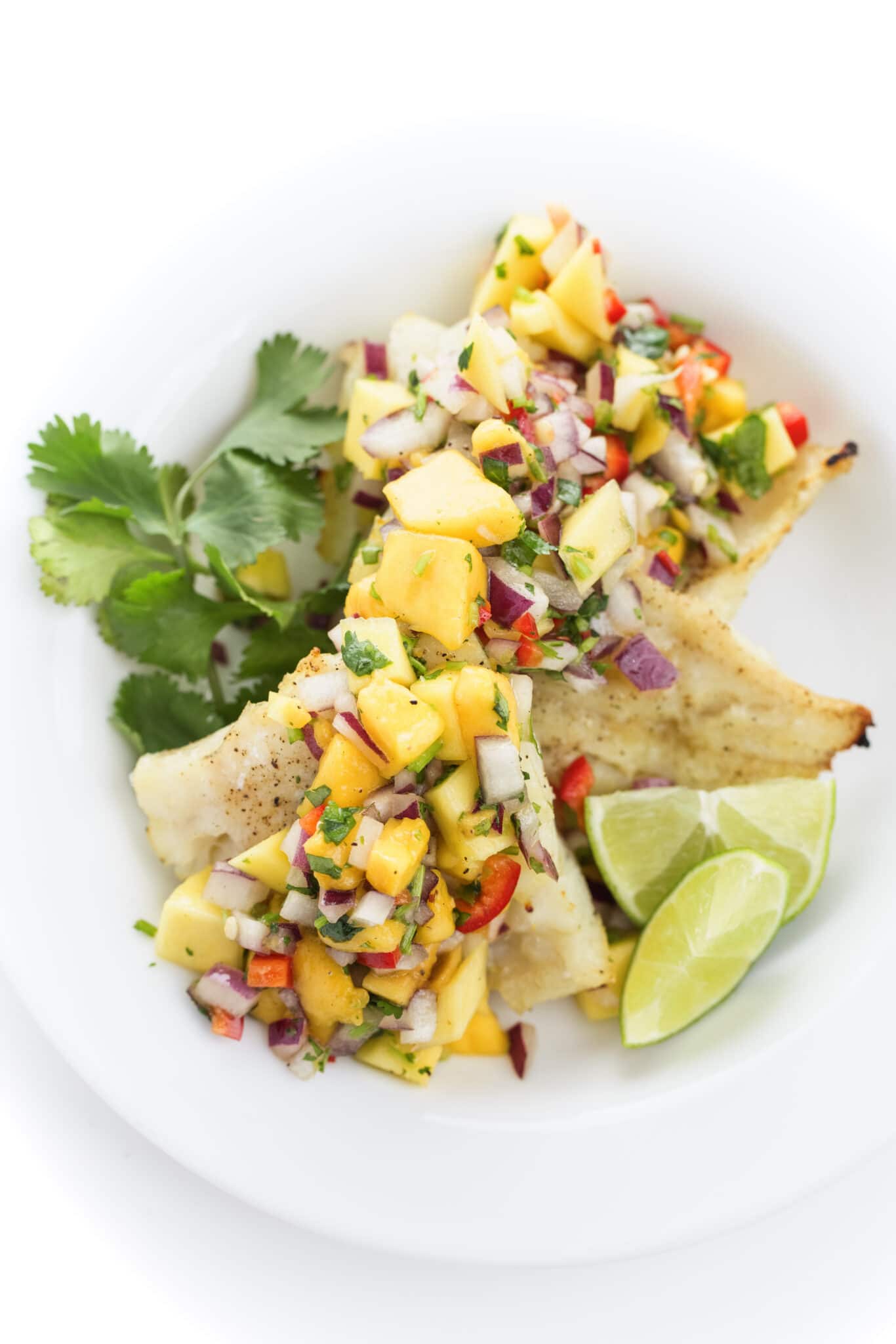 Broiled Whitefish with Mango Salsa on a white plate.