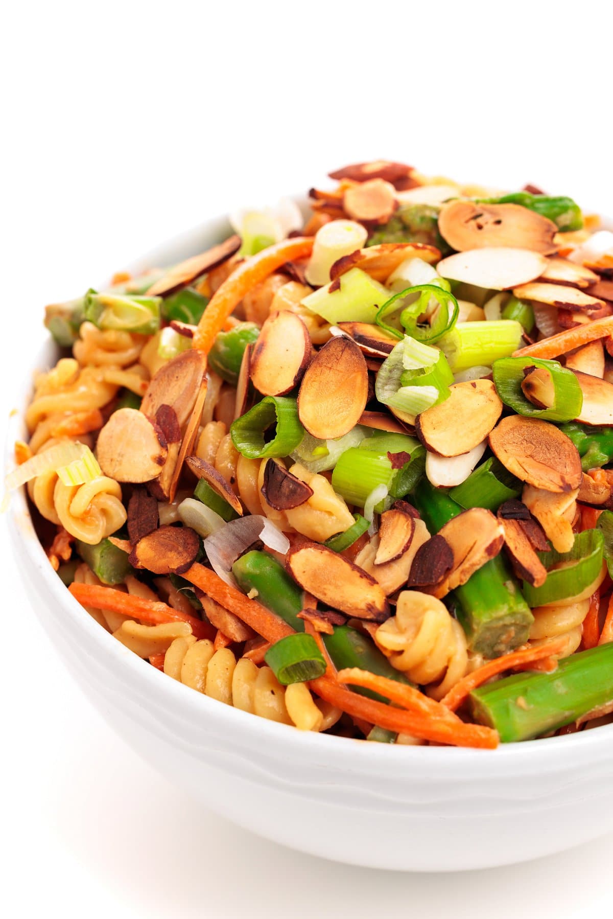 Asparagus pasta salad topped with sliced almonds and scallions.