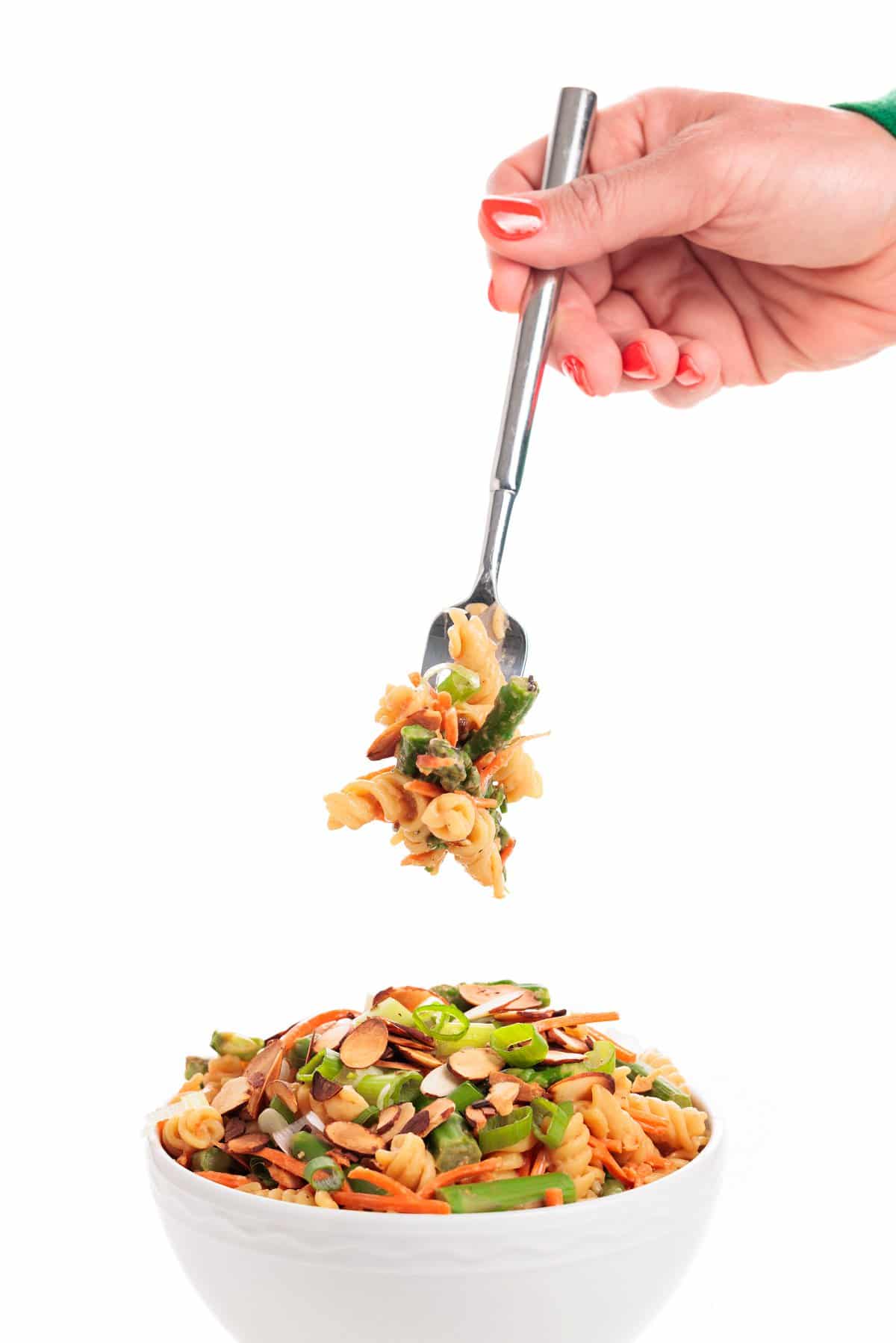 A forkful of asparagus pasta salad over a white bowl full of it.