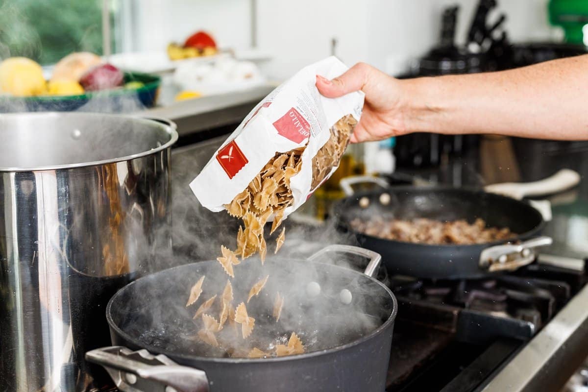 Adding pasta to boiling water in large pot.