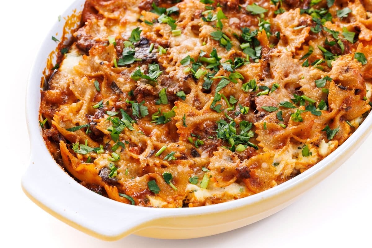 Sausage and eggplant baked pasta garnished with freshly minced herbs.