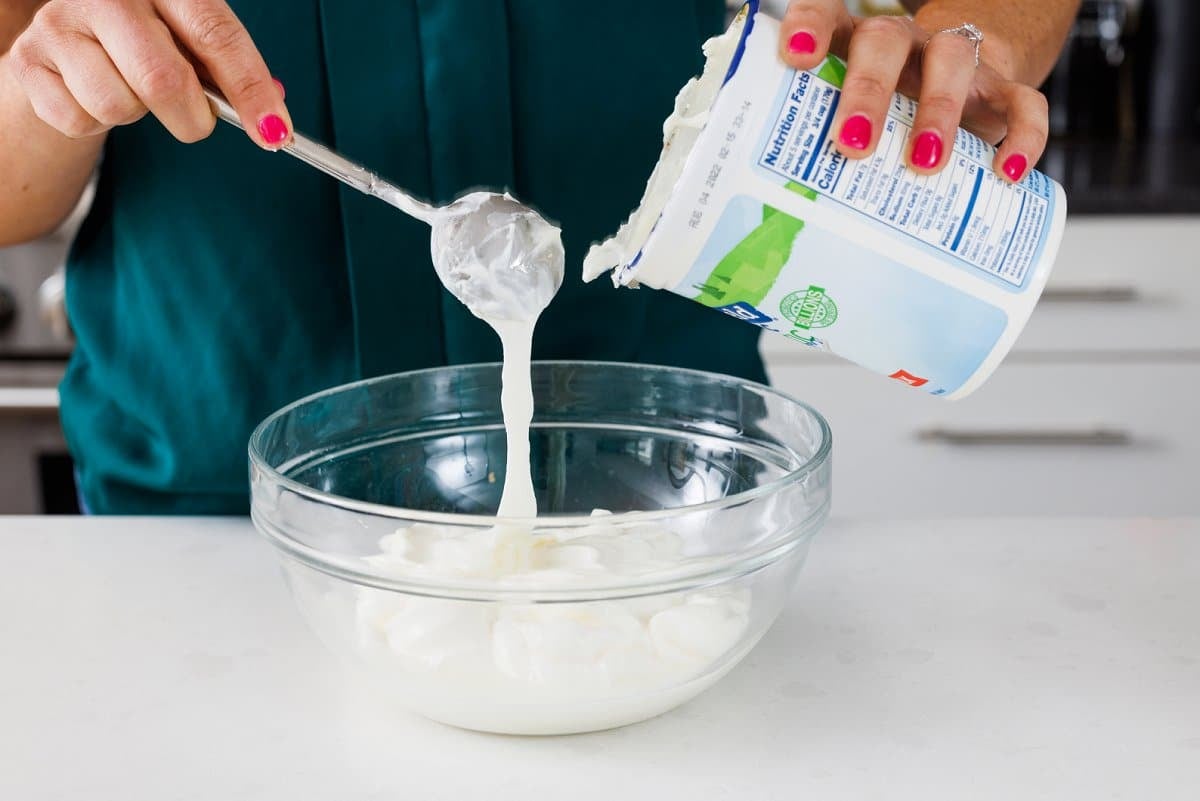 Adding yogurt to a bowl.