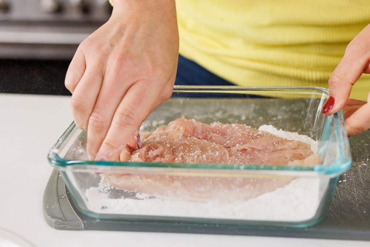 Coating chicken in flour.