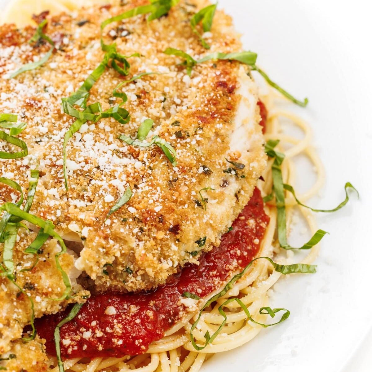 Oven baked chicken parmesan over a bed of pasta.