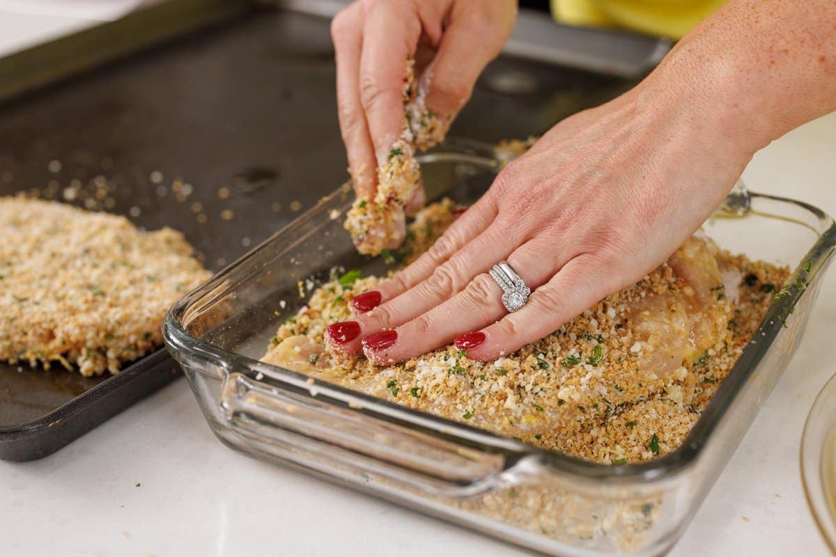 Pressing chicken into panko bread crumb mixture.
