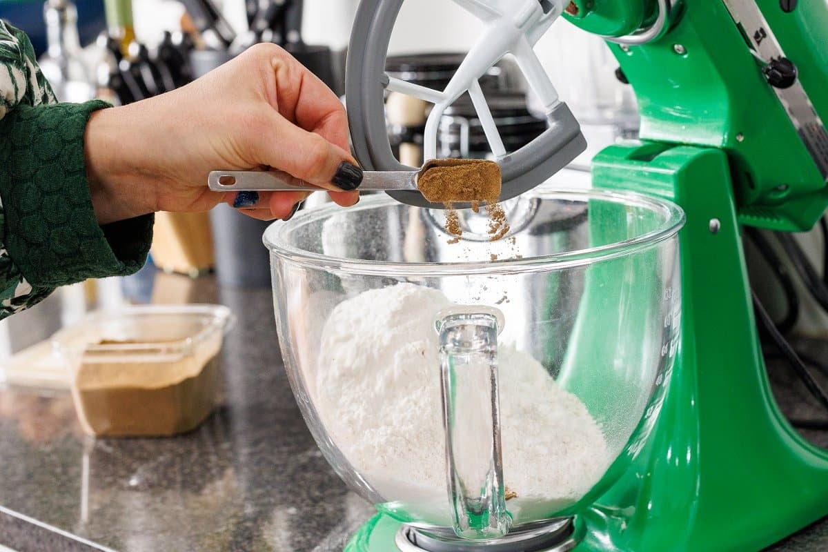 Adding cinnamon to a mixing bowl of flour.