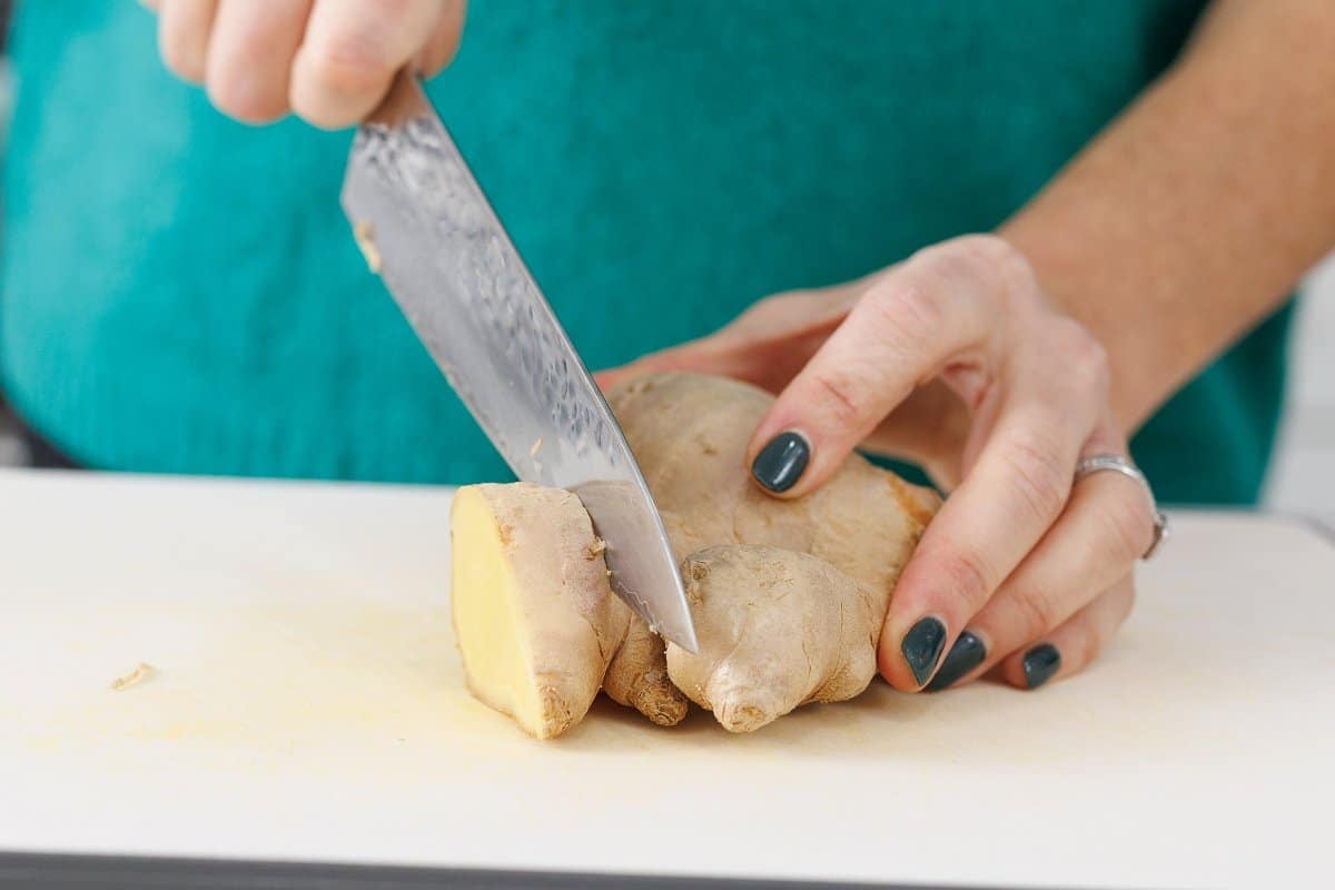 Liz cutting fresh ginger on a cutting board.