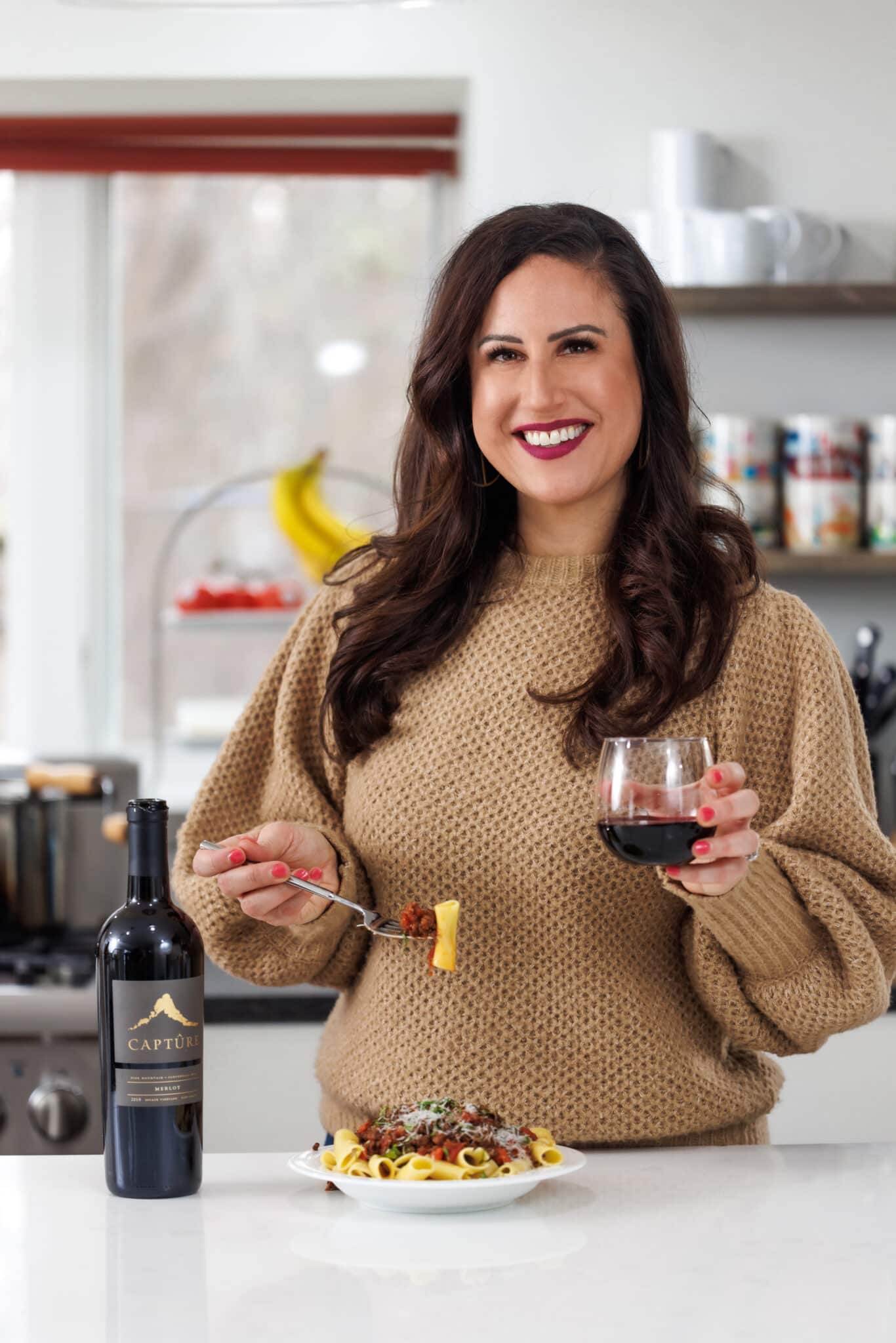 Liz drinking Capture wine and eating beef bolognese.