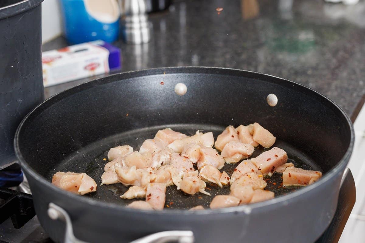 Cooking cut up chicken in a deep skillet.