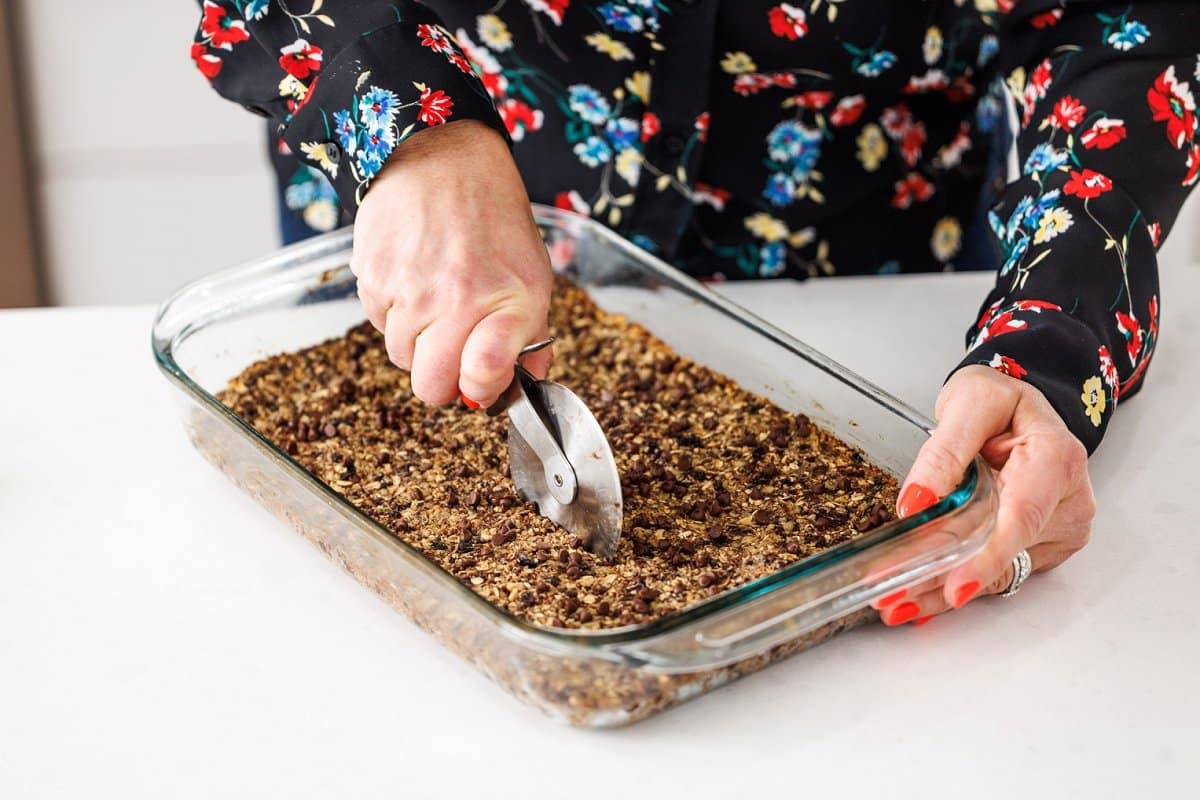 Cutting baked granola bars with a pizza cutter.