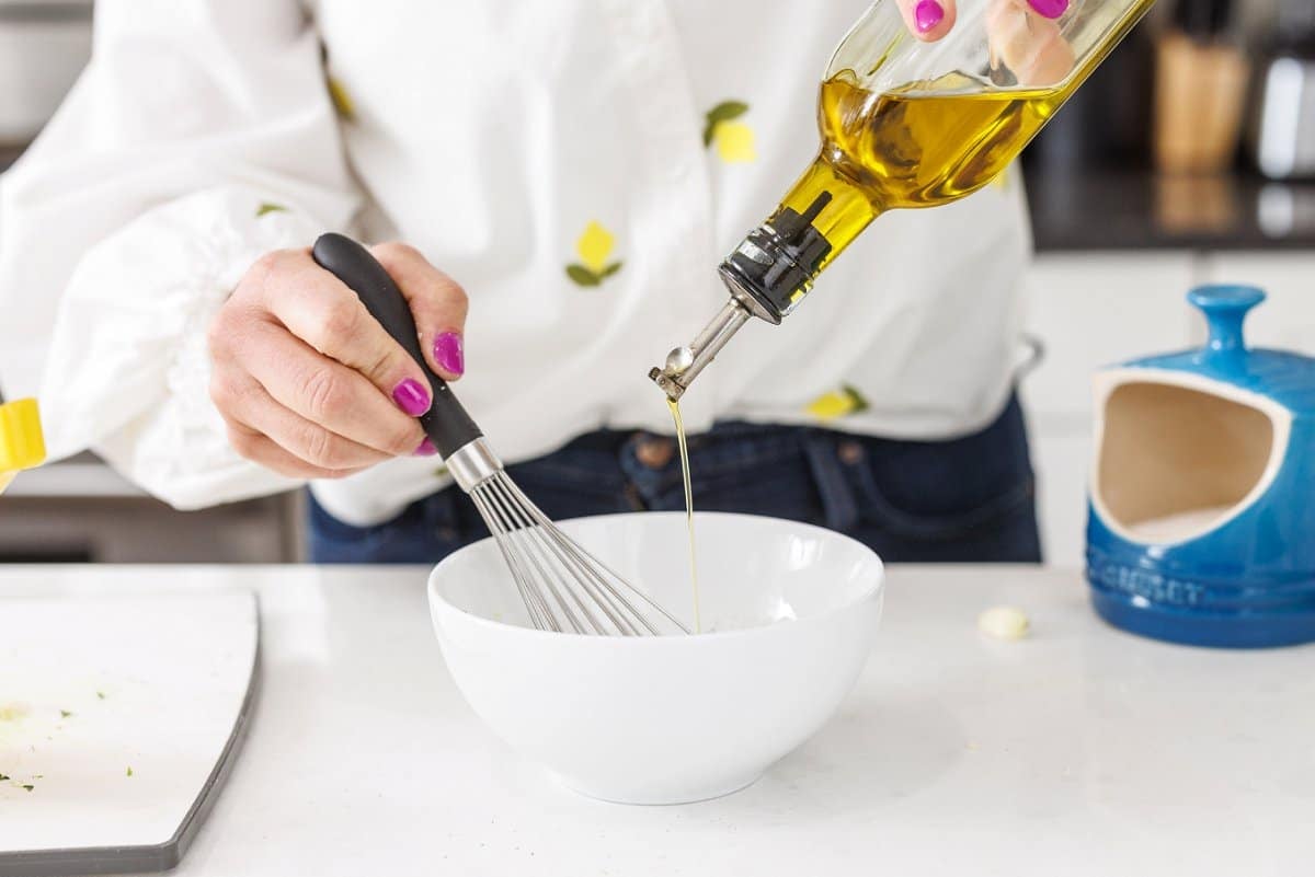 Whisking olive oil into salad dressing.