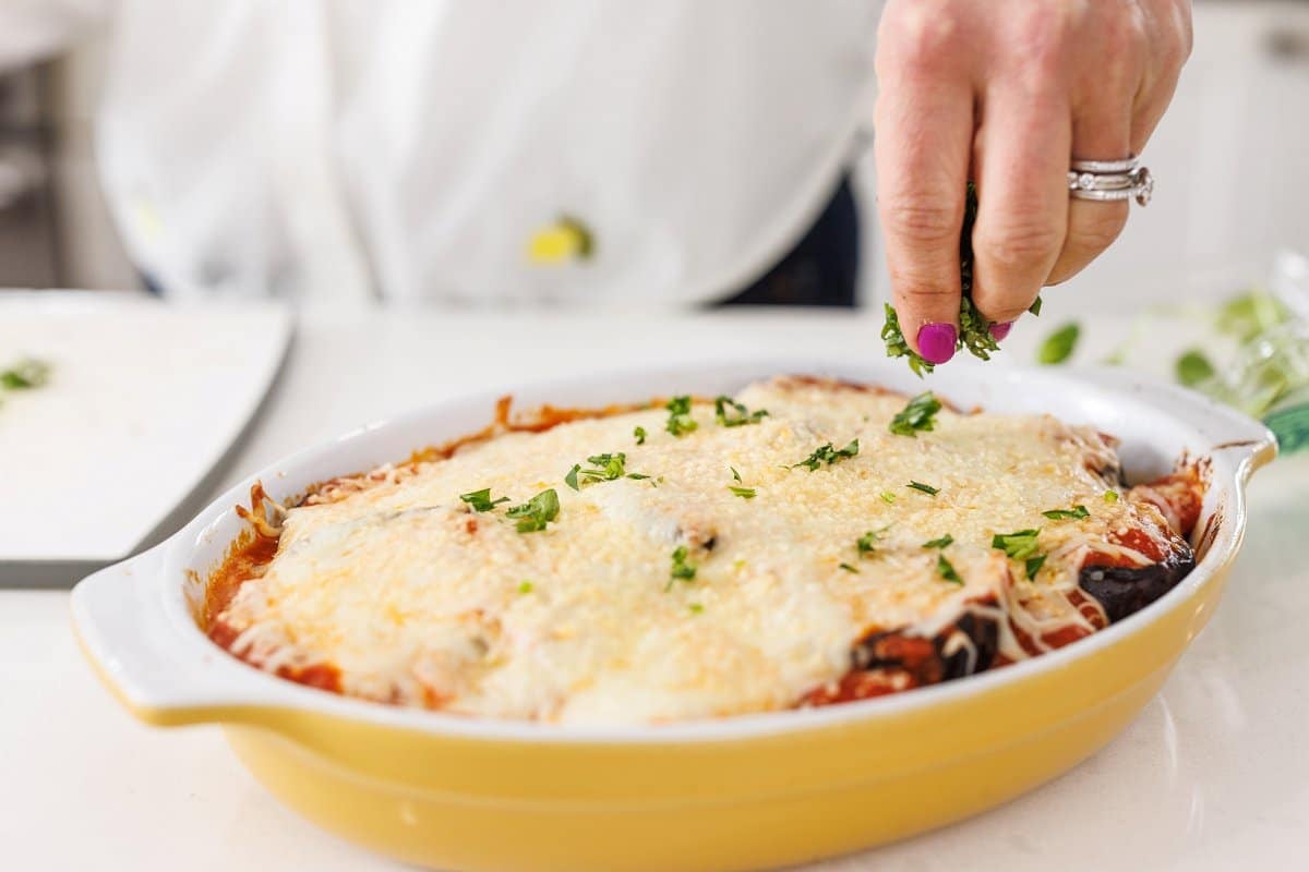 Garnishing grilled eggplant parmesan with fresh parsley.
