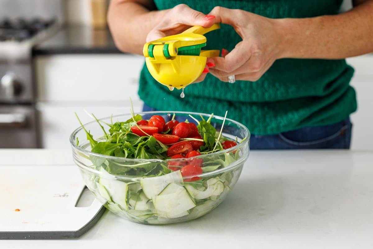 Using a lemon juicer to squeeze fresh lemon juice onto a salad.