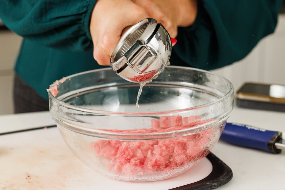 Using a lemon squeezer to add lime juice to tuna.