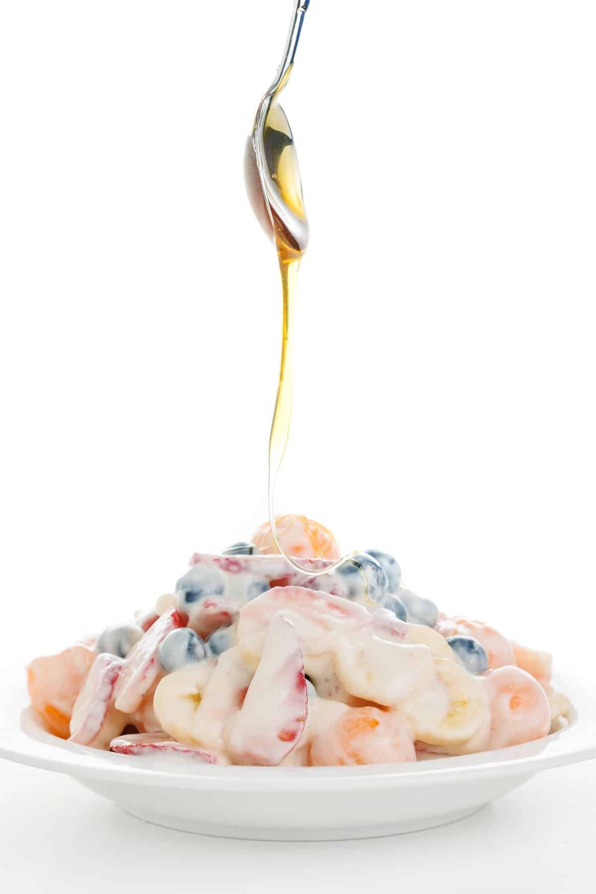 Drizzling honey on fruit salad with honey yogurt dressing.