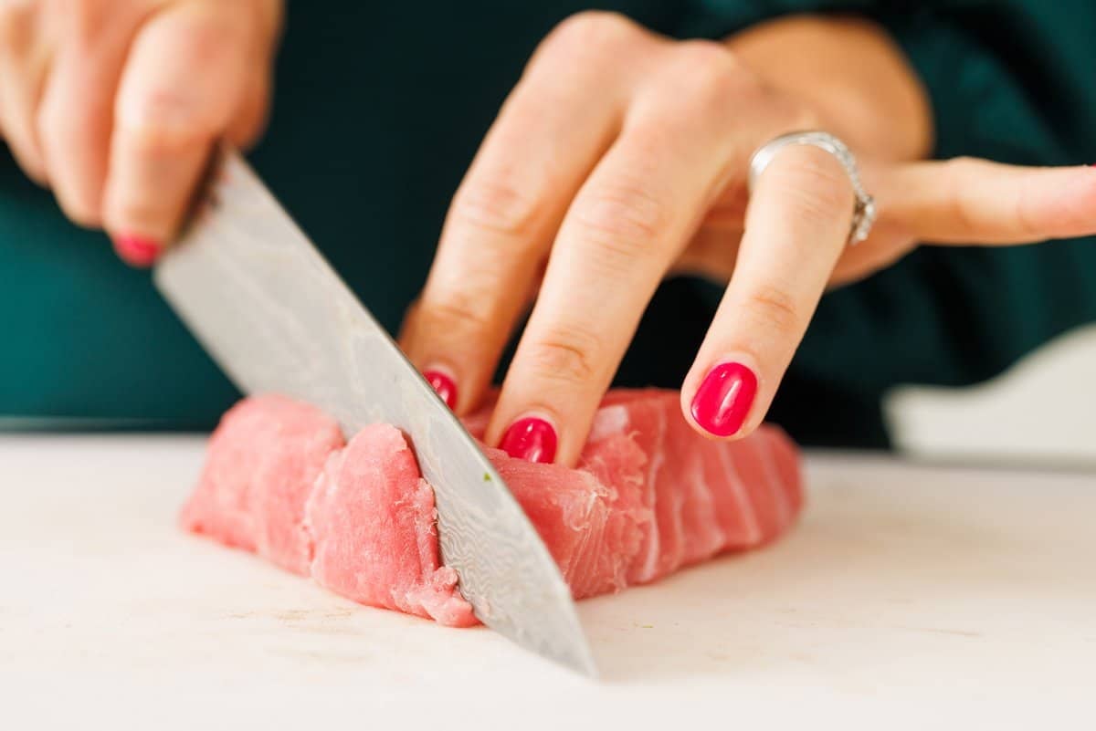 Slicing raw tuna fillet with a sharp knife.