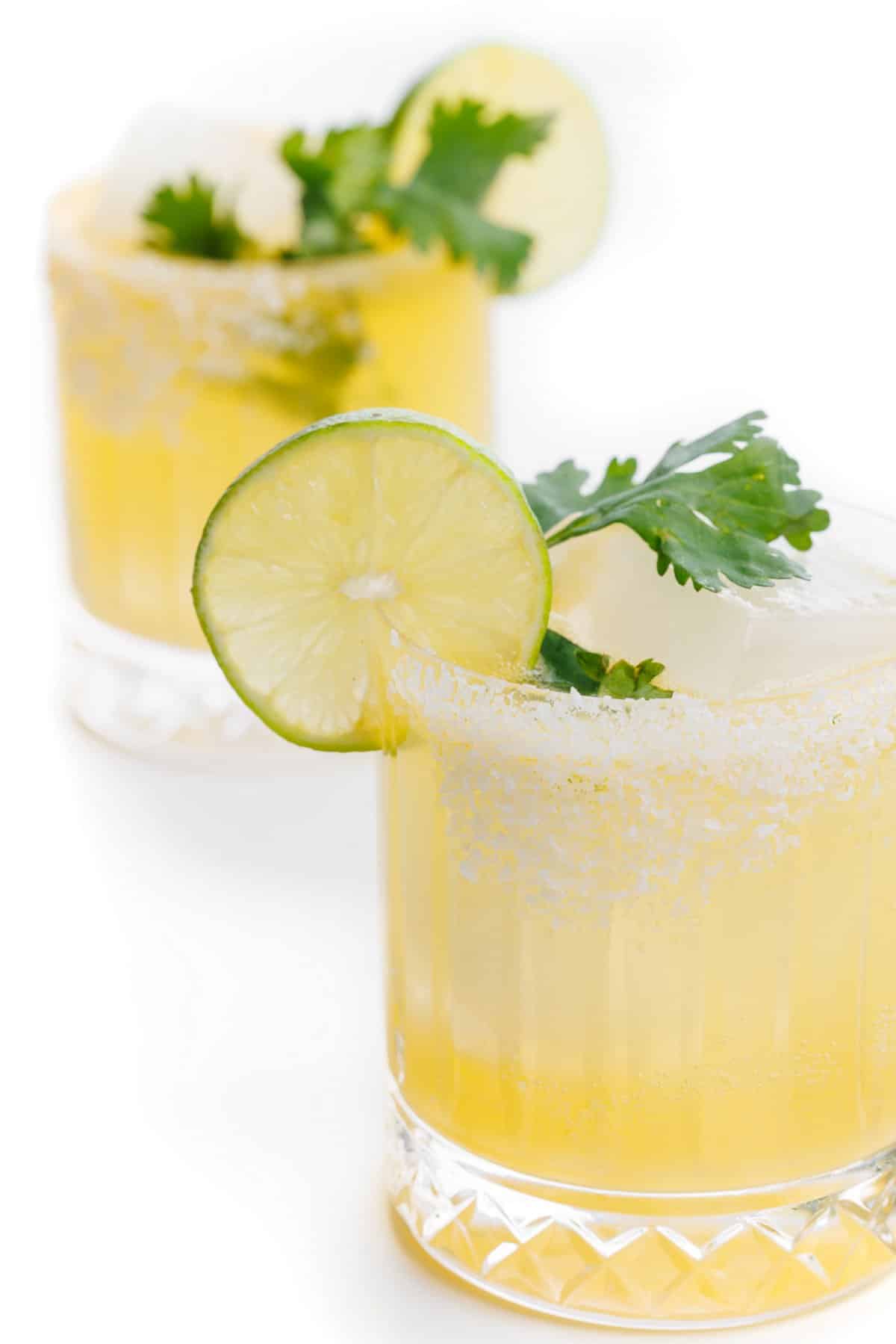 Cilantro margaritas with salted rims and fresh lime and cilantro garnishes.