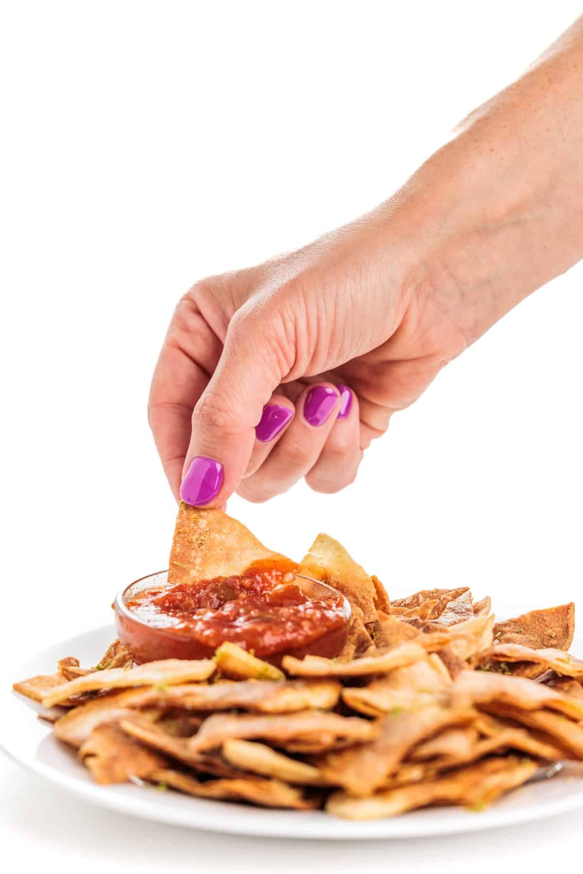 Dipping lime baked tortilla chips in salsa.
