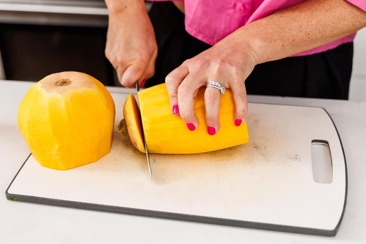 Trimming top off of butternut squash with a sharp knife.