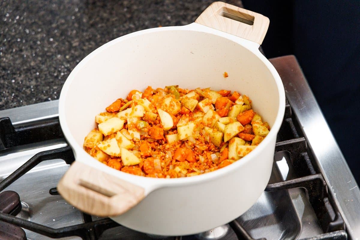Red lentils in a pot of cooked veggies.