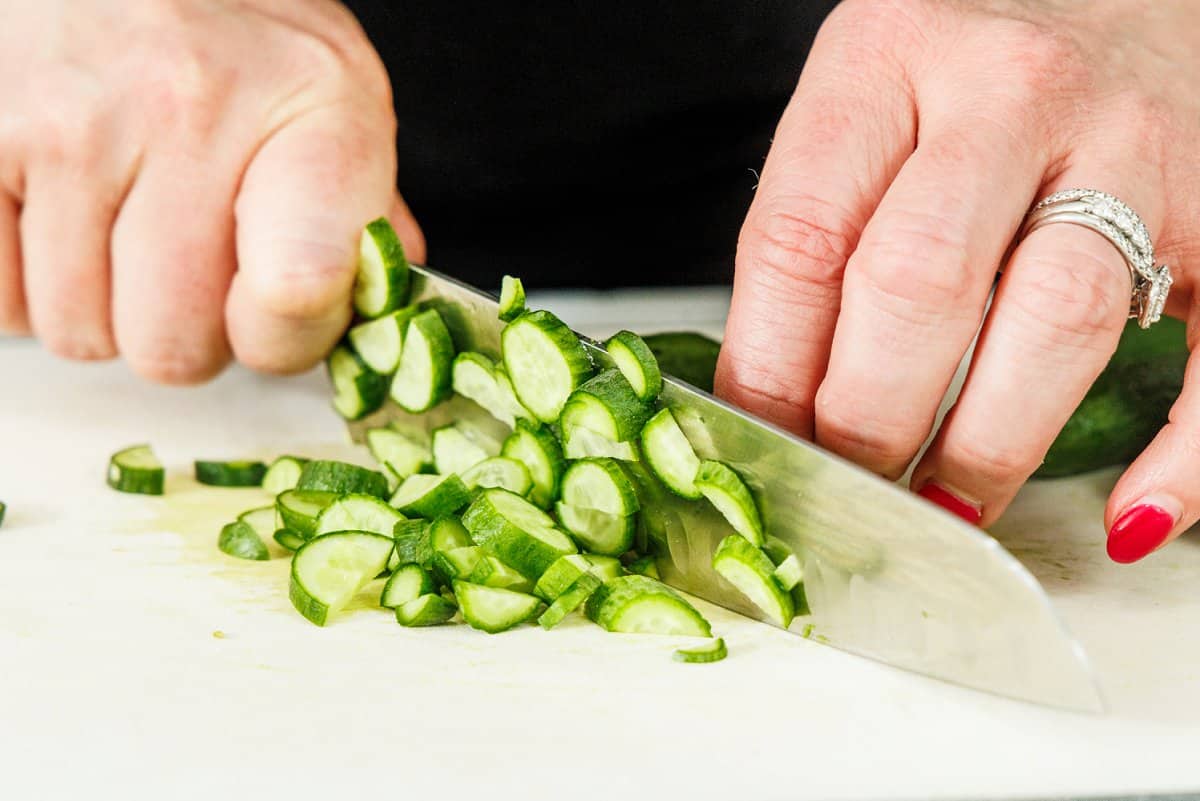 Cutting baby cucumbers into thin, small pieces with a knife.
