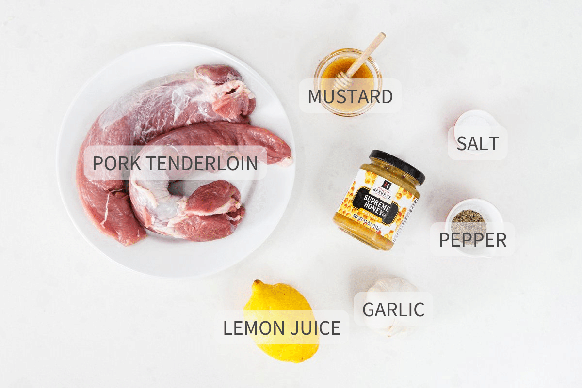 Ingredients for pork tenderloin, labeled, on top of a white backdrop.