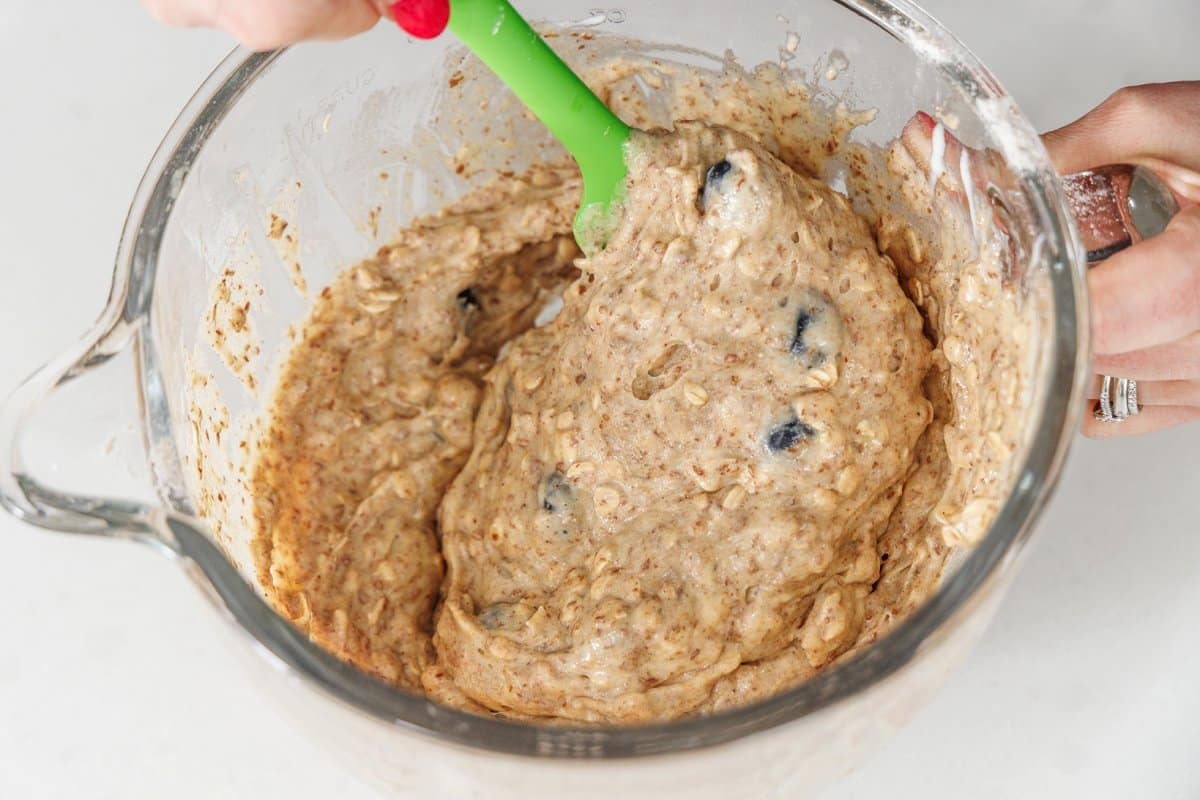 Folding fresh blueberries into bread batter with a rubber spatula.