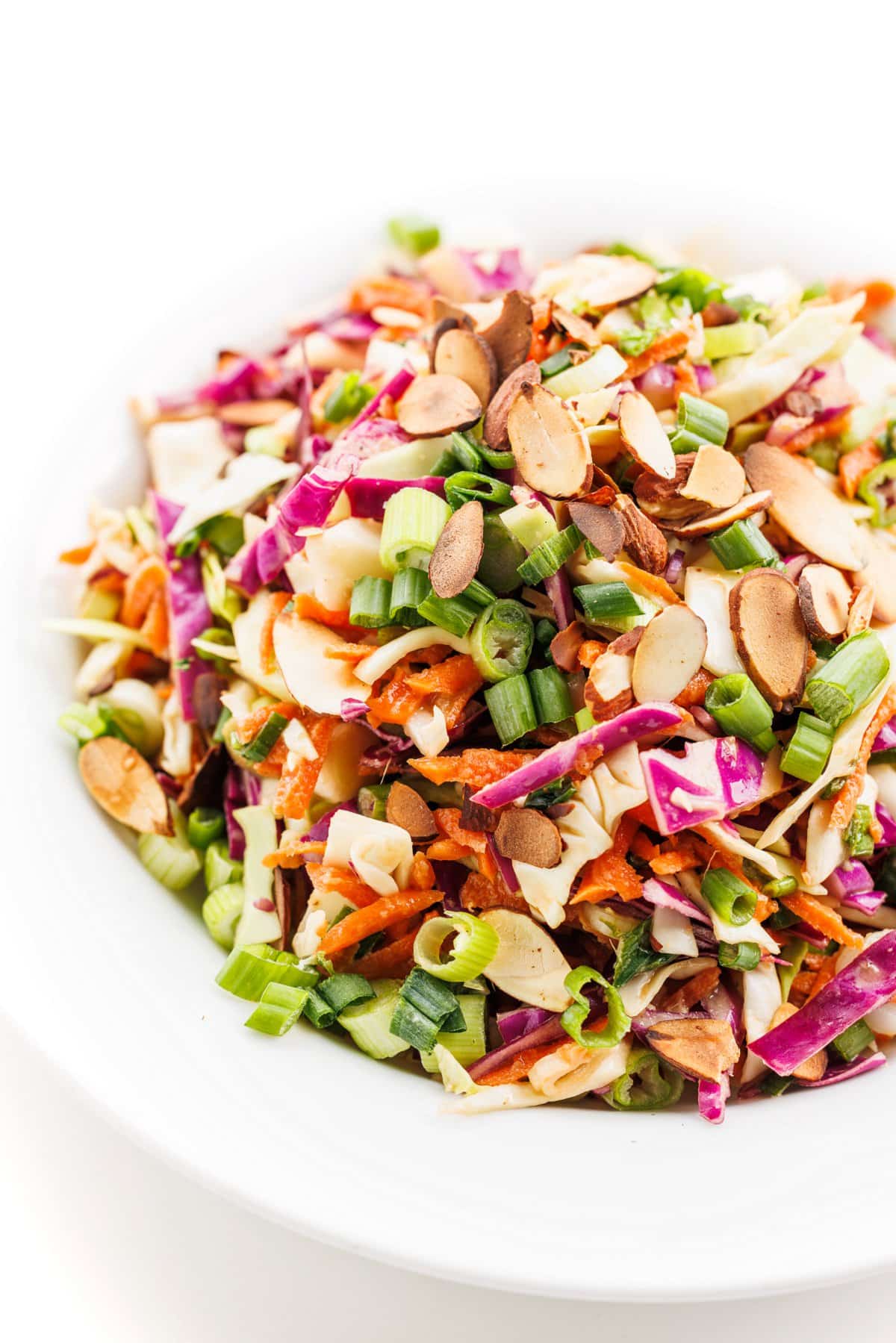 Spicy Asian coleslaw topped with toasted almonds in a white bowl.