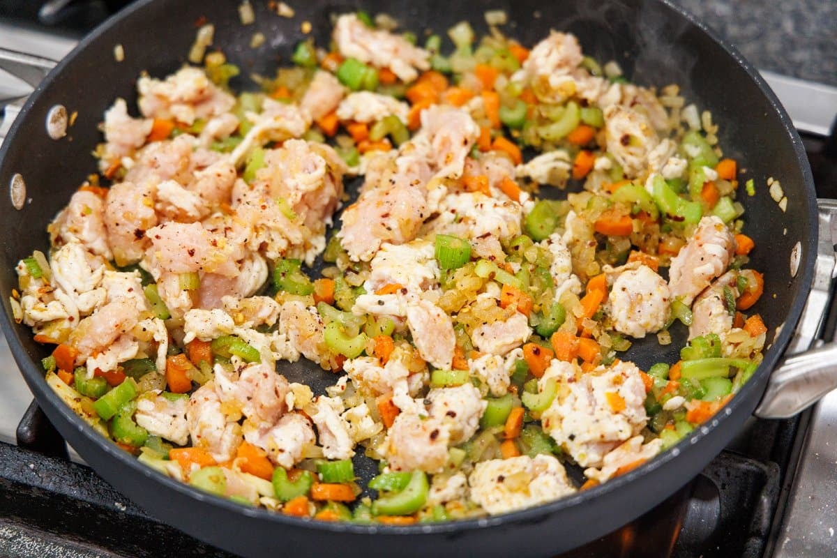 Adding ground turkey to sautéed vegetables.