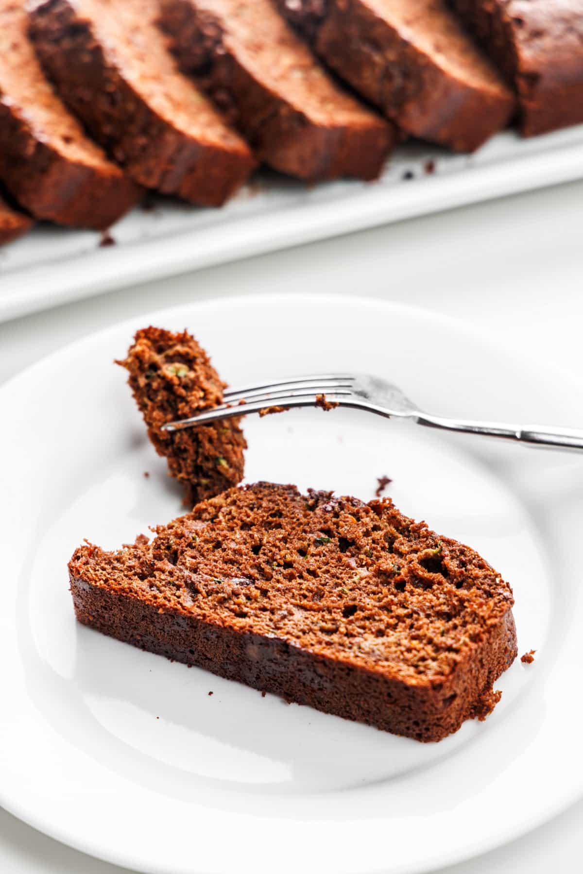A slice of chocolate zucchini carrot bread on a plate with a fork.