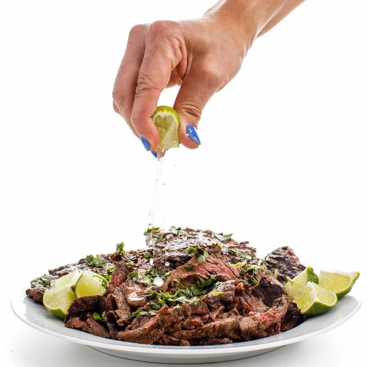 Garnishing carne asada marinade with lime juice.