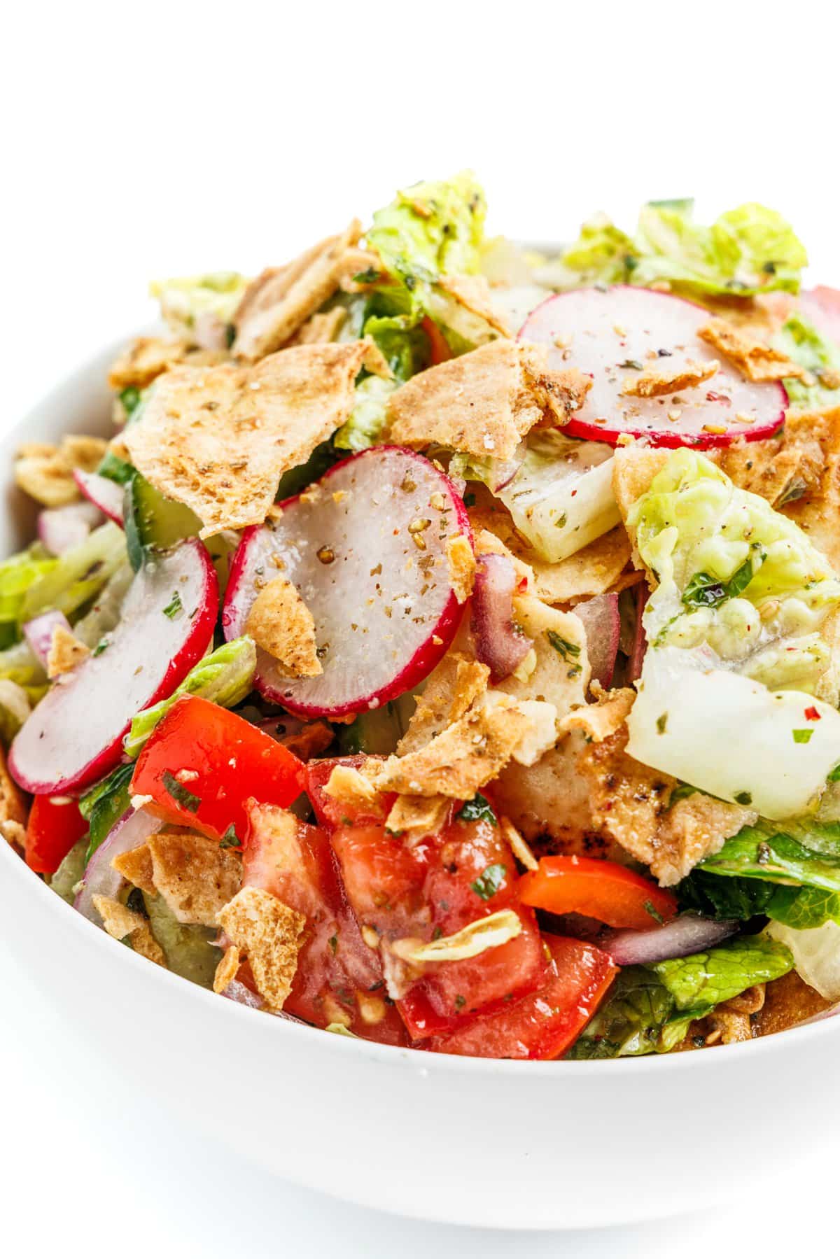 Close up of Lebanese fattoush salad topped with broken up baked pita chips and za'atar spice.