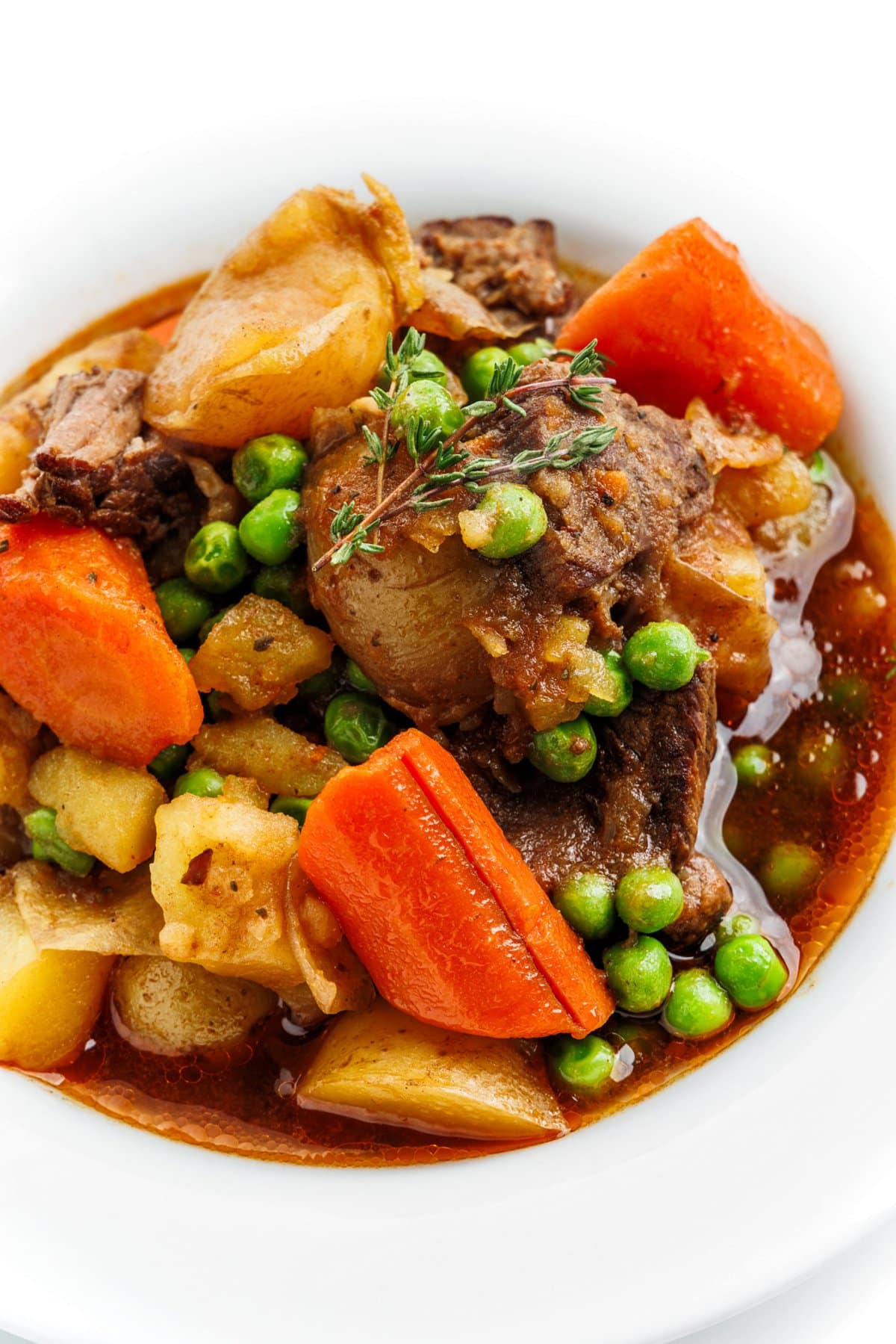 Slow cooker Irish beef stew garnished with a sprig on thyme.