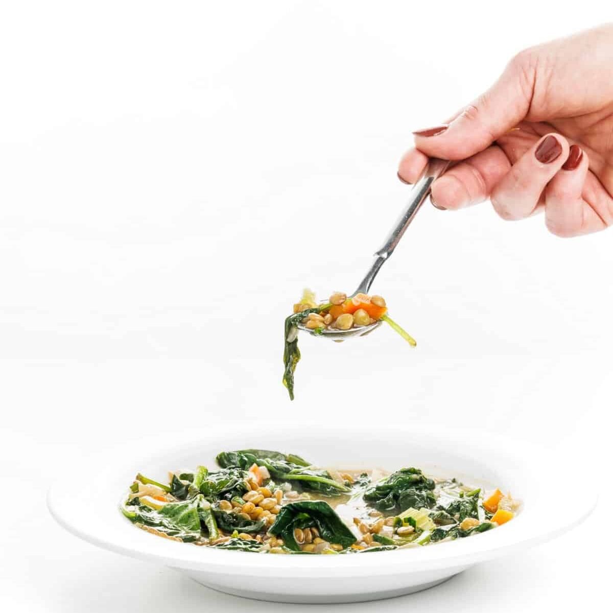 Spoonful of Lebanese lentil soup with greens.