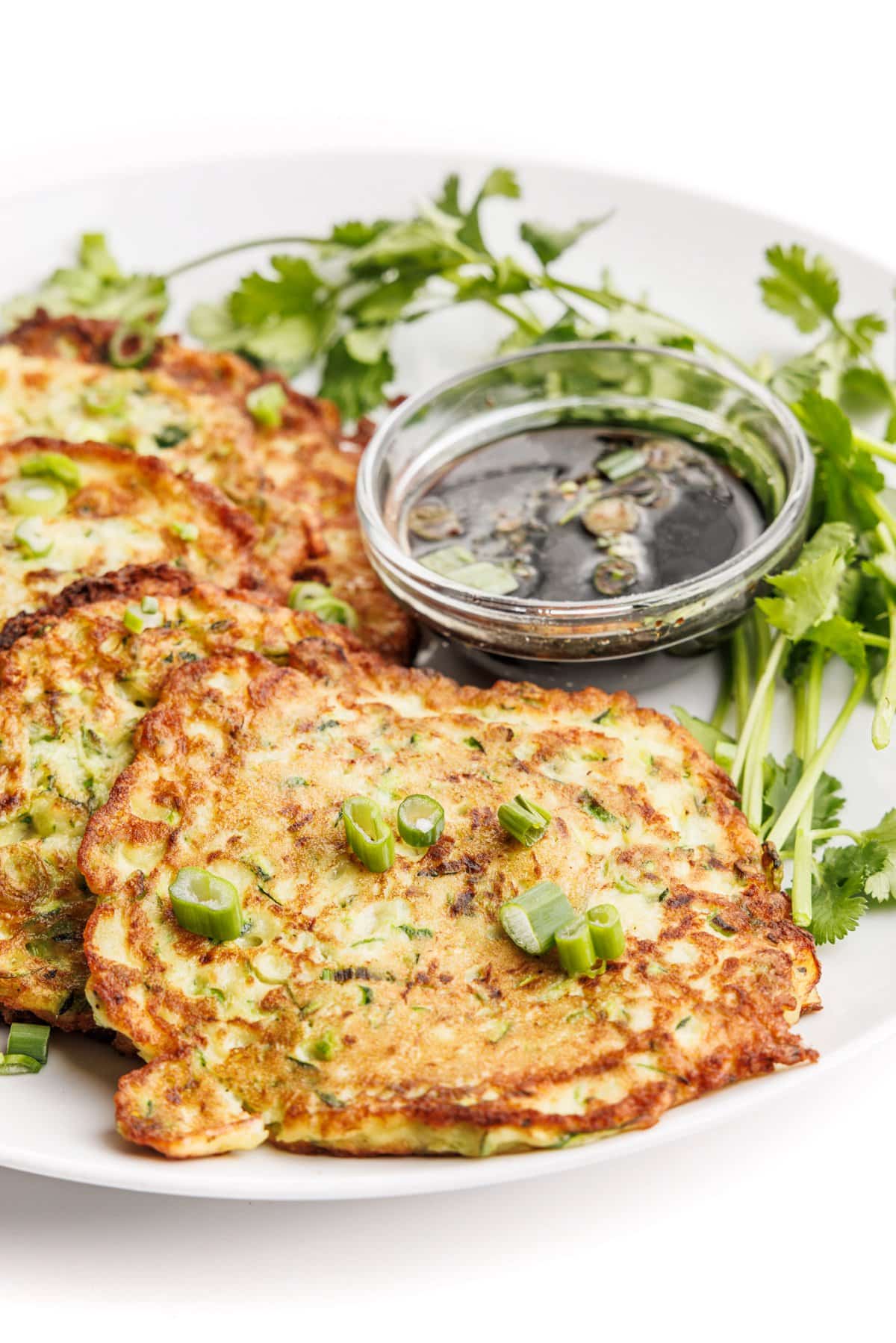 Zucchini scallion pancakes garnished with fresh scallions and parsley sprigs.