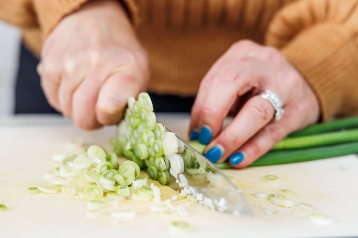 Liz cutting scallions into small slices with a sharp knife.