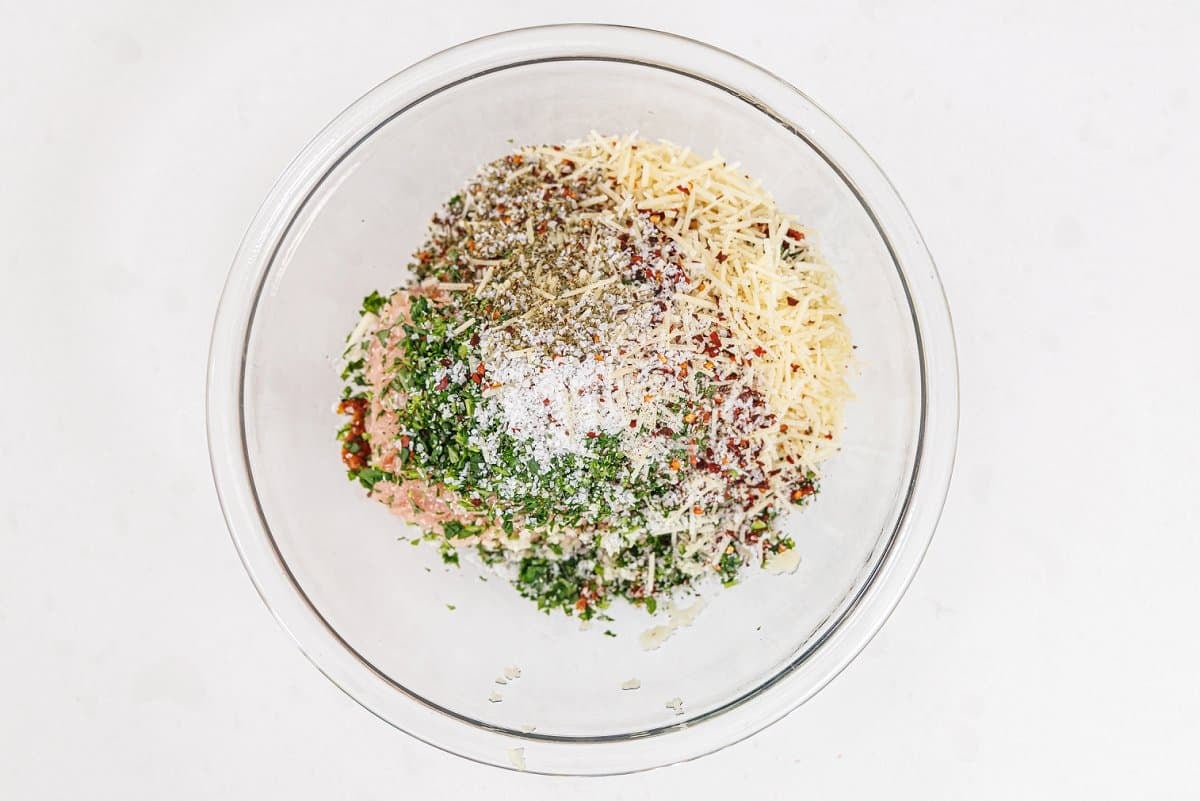 Glass bowl full of ingredients for meatloaf muffins.